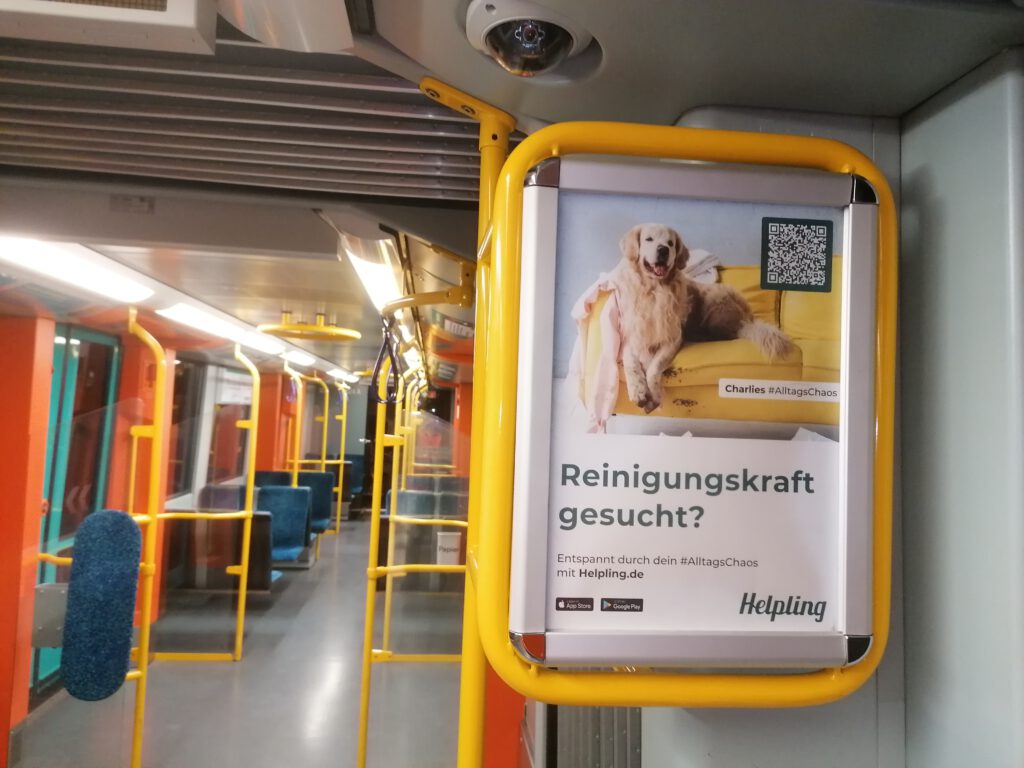 Verkehrsmittelwerbung 16 Stadtbahn-Werbung: Innenplakat im Rahmen an der Haltestange (Kampagne Helpling, VGF Frankfurt)