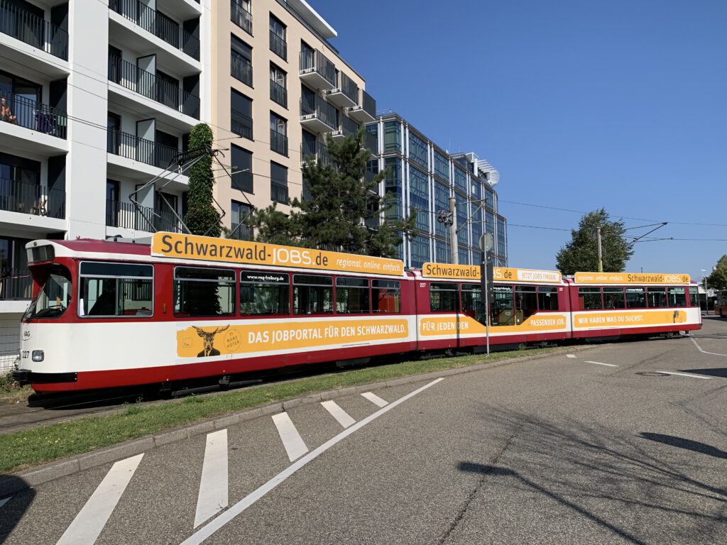Verkehrsmittelwerbung 11 Straßenbahnwerbung Teilgestaltung mit Dachkranz auf Niederflur-Straßenbahn (Kampagne Lokale Stimme)